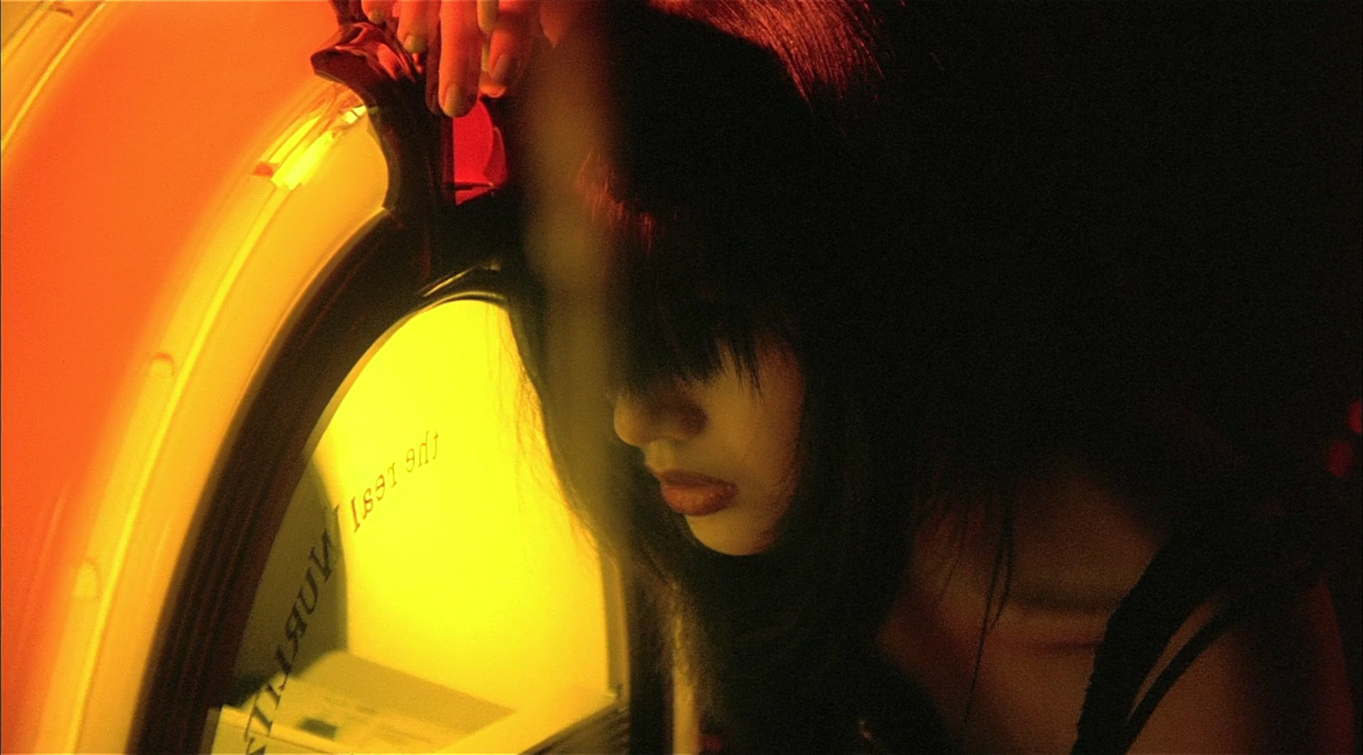 Eine Frau mit langen schwarzen Haaren vor einer Jukebox.